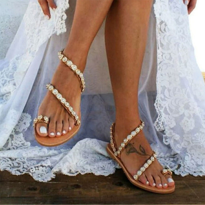 Bruine sandalen met parels en strass, gedragen door vrouw in witte kanten jurk. Perfect voor zomermode en strandbruiloften.