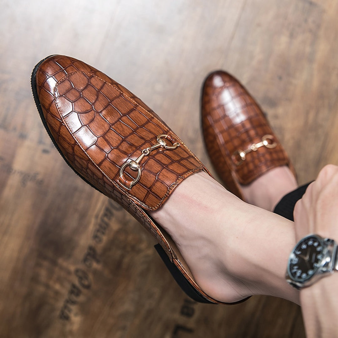 Bruine leren loafers met krokodillenprint en gouden gesp, gedragen op houten vloer. Stijlvolle herenschoenen, luxe design, modieuze accessoires.