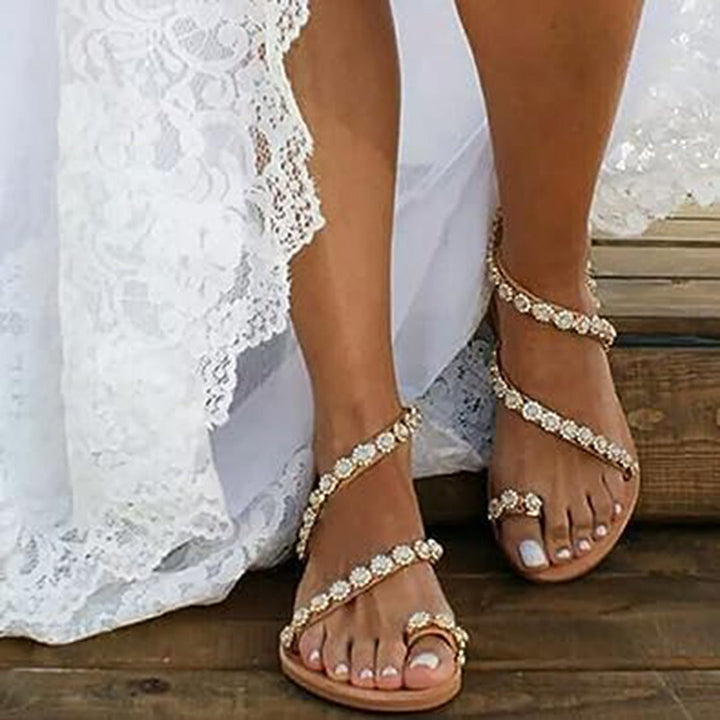 Bruine sandalen met strass steentjes, gedragen door een vrouw in een witte kanten jurk. Perfect voor zomerse bruiloften en strandfeesten.