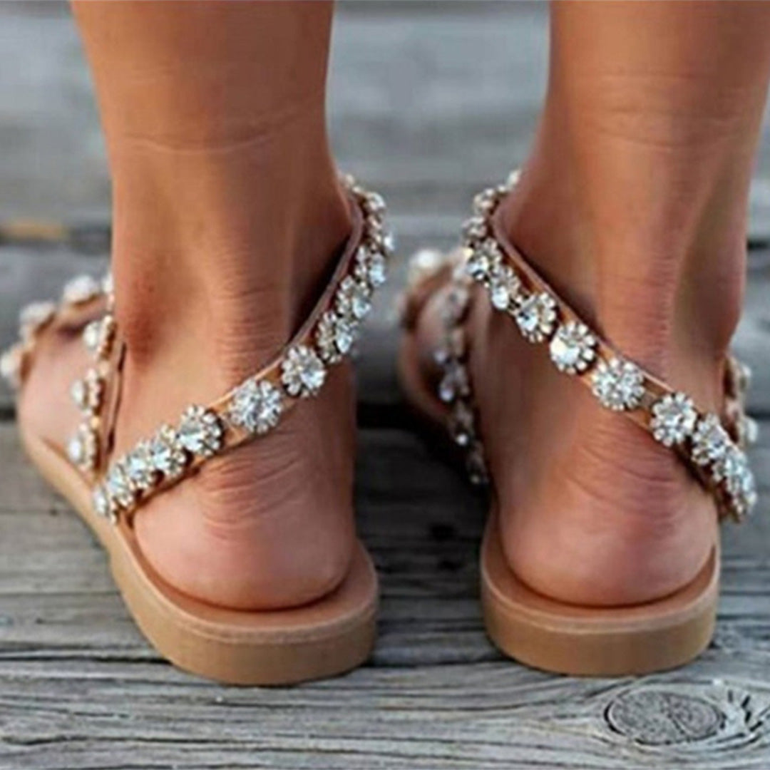Bruine sandalen met bloemenstrass op houten vloer, zomerschoeisel voor dames, modieuze en comfortabele sandalen, perfect voor casual en stranduitjes.