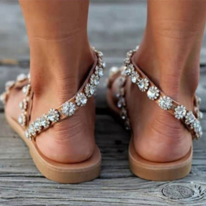 Bruine sandalen met bloemenstrass op houten vloer, zomerschoeisel voor dames, modieuze en comfortabele sandalen, perfect voor casual en stranduitjes.