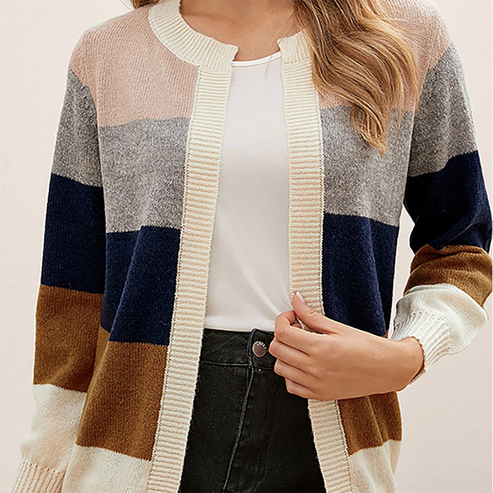Vrouw draagt een gestreept vest in bruin, blauw, grijs en roze tinten, gecombineerd met een witte top en zwarte broek. Modieuze dameskleding.