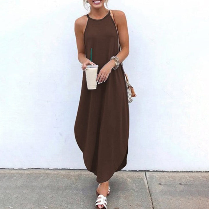 Vrouw in bruine maxi-jurk met halternek, houdt een ijskoffie vast. Zomerse outfit, casual stijl, perfect voor warme dagen. Comfortabele sandalen.