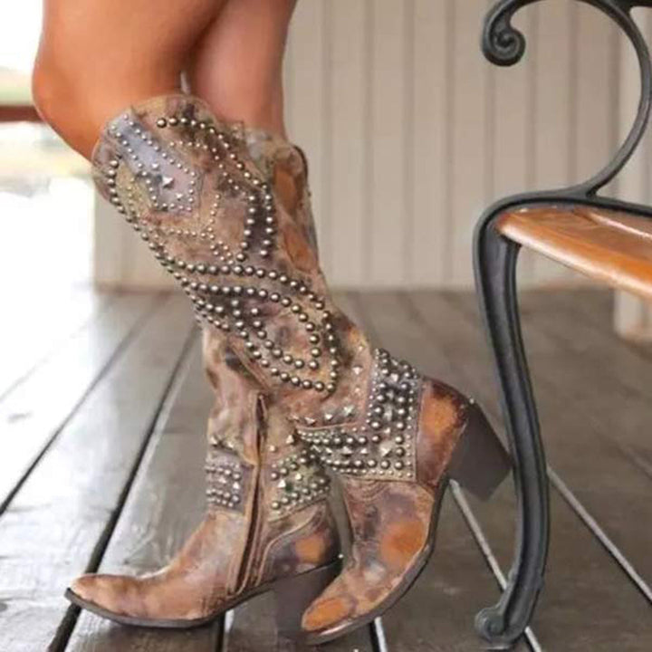 Bruine leren cowboylaarzen met studs, damesmode, westerse stijl, hoge hakken, vintage design, houten vloer, trendy laarzen voor herfst.