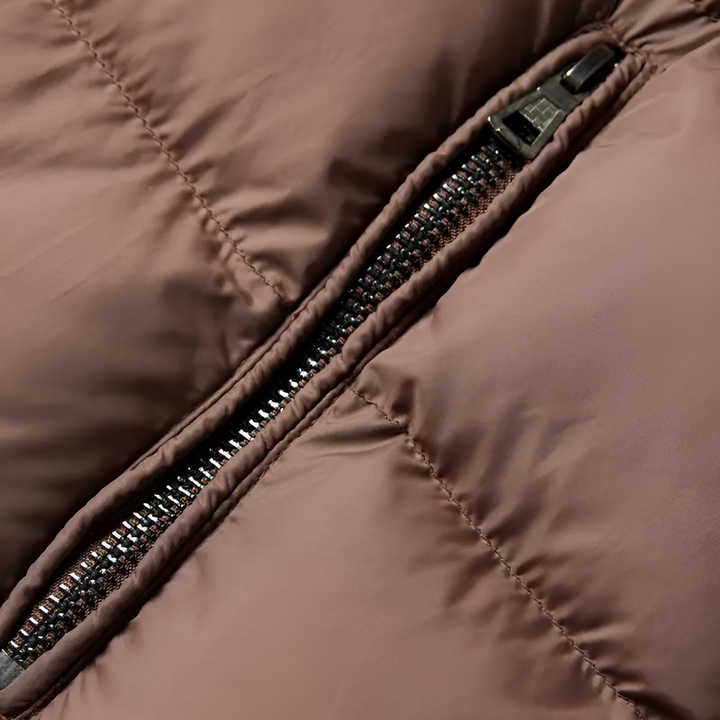 Close-up van een bruine gewatteerde jas met rits, detail van de stof en stiksels. Winterjas, warme kleding, modetrend, duurzame materialen.