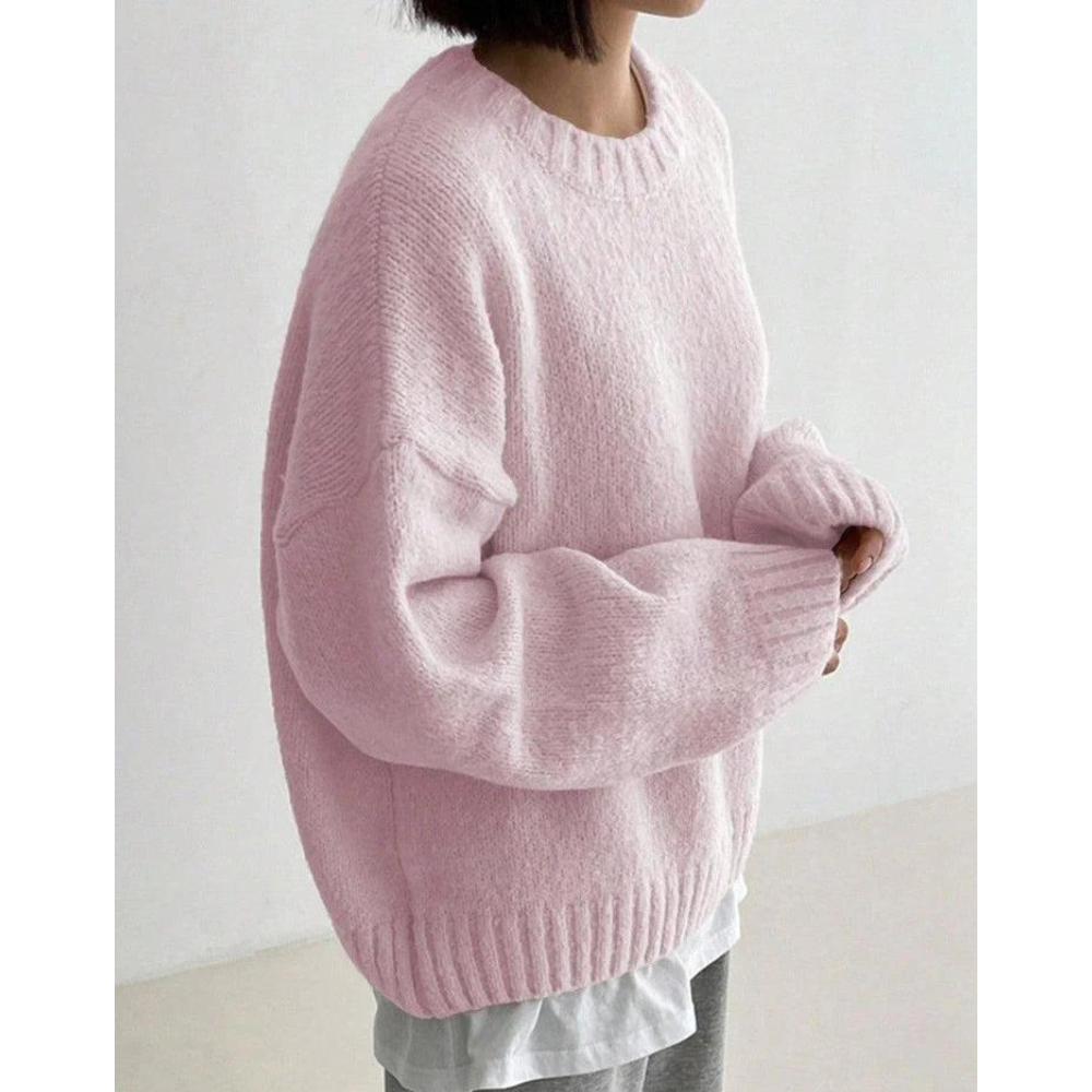 Vrouw draagt oversized roze trui, gebreid, met ronde hals. Modieuze dameskleding, casual stijl, comfortabele winteroutfit.
