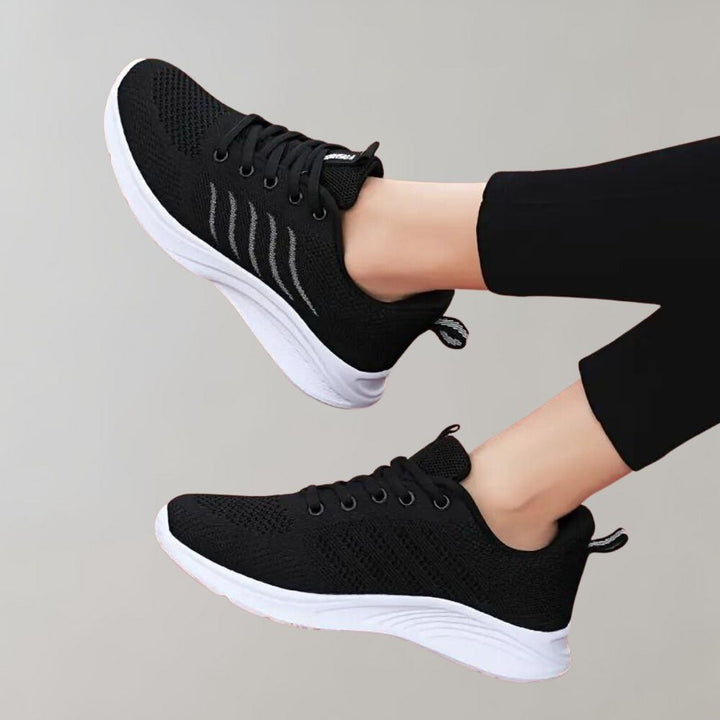 Zwarte sportschoenen met witte zool, ademend mesh bovenwerk en gestreept detail, ideaal voor hardlopen en fitness. Comfortabele en stijlvolle sneakers.