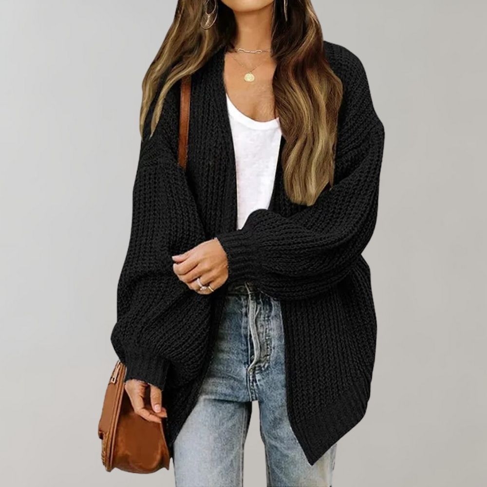Zwarte gebreide damescardigan, oversized pasvorm, gecombineerd met witte top en jeans. Perfect voor casual herfst- en winteroutfits.