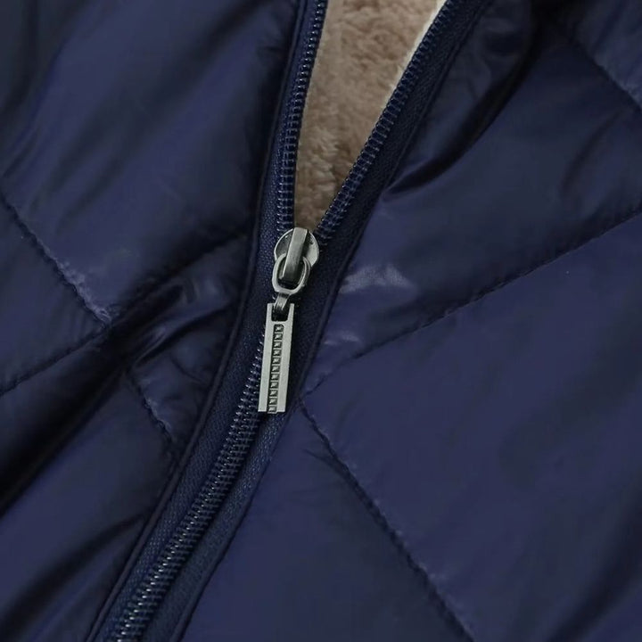 Donkerblauwe gewatteerde jas met ritssluiting, close-up. Hoogwaardige winterjas, warme voering, modieuze en functionele buitenkleding.