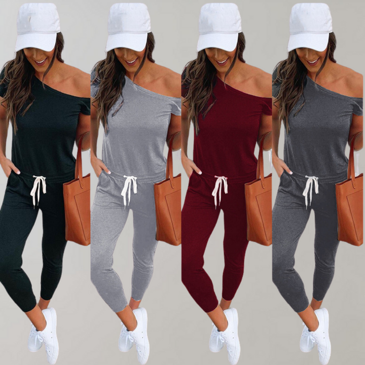 Vrouw in off-shoulder jumpsuit, verkrijgbaar in zwart, grijs, rood, met witte pet en sneakers. Modieuze dameskleding, casual stijl.