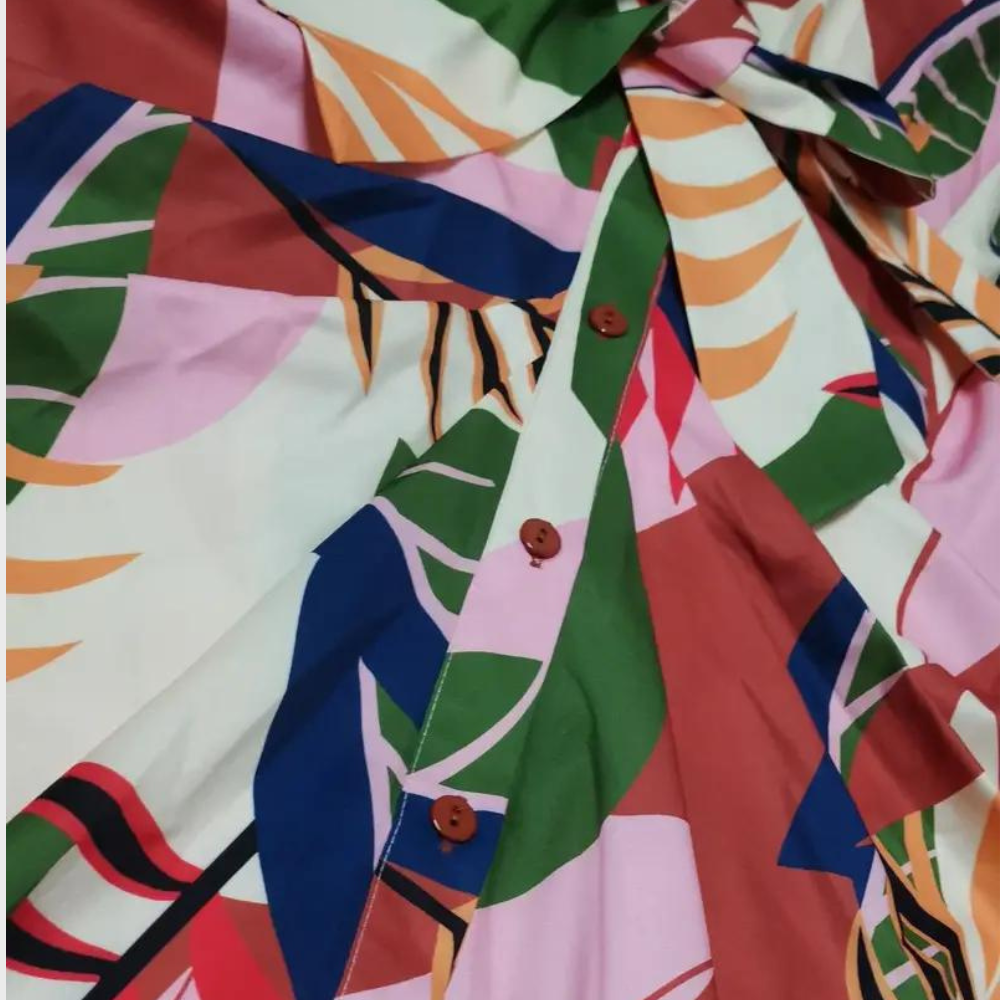 Abstracte kleurrijke stof met geometrische patronen, waaronder bladeren en lijnen in roze, groen, blauw en bruin. Ideaal voor modeontwerp en interieur.