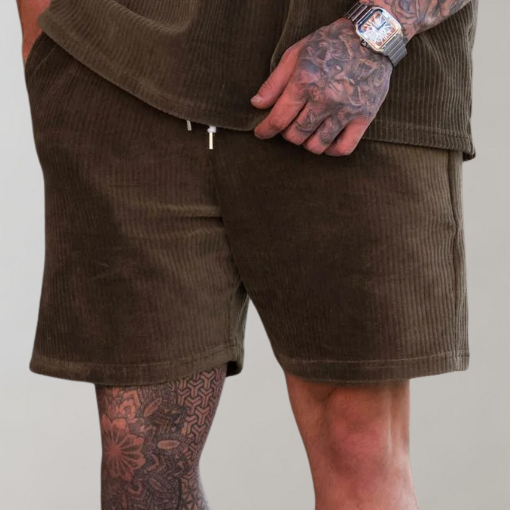 Bruine corduroy korte broek voor heren, gedragen door een getatoeëerde man. Comfortabele pasvorm, ideaal voor casual zomeroutfits.