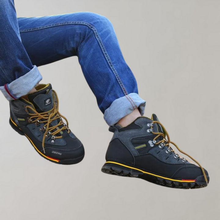 Zwarte wandelschoenen met gele accenten en stevige zolen, gedragen met opgerolde blauwe jeans. Ideaal voor outdoor avonturen en trekking.
