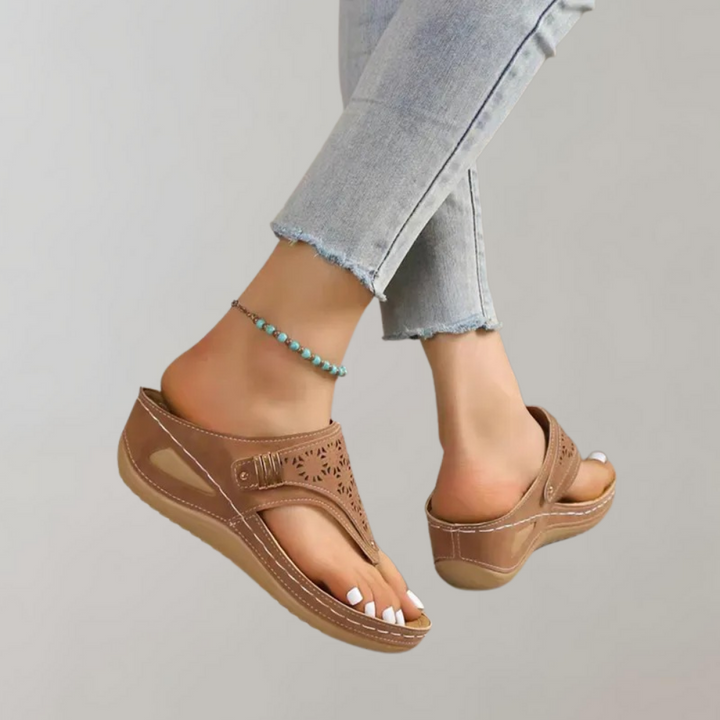 Bruine leren dames sandalen met sleehak, open teen en geperforeerd bloemmotief. Comfortabele zomerschoenen, perfect voor casual outfits.