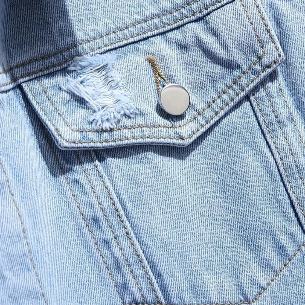 Lichtblauwe spijkerjas met borstzak, versierd met een metalen knoop en rafelige scheur. Trendy denim mode, casual stijl.