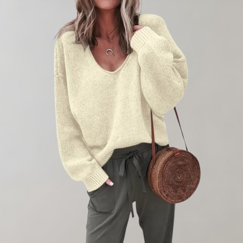Vrouw in beige trui met V-hals, groene broek en ronde rieten tas. Modieuze dameskleding, casual herfstoutfit, trendy accessoires.