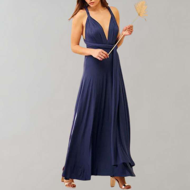Donkerblauwe avondjurk met diepe V-hals en plooien, gedragen door model met gouden sandalen. Perfect voor elegante evenementen en feesten.