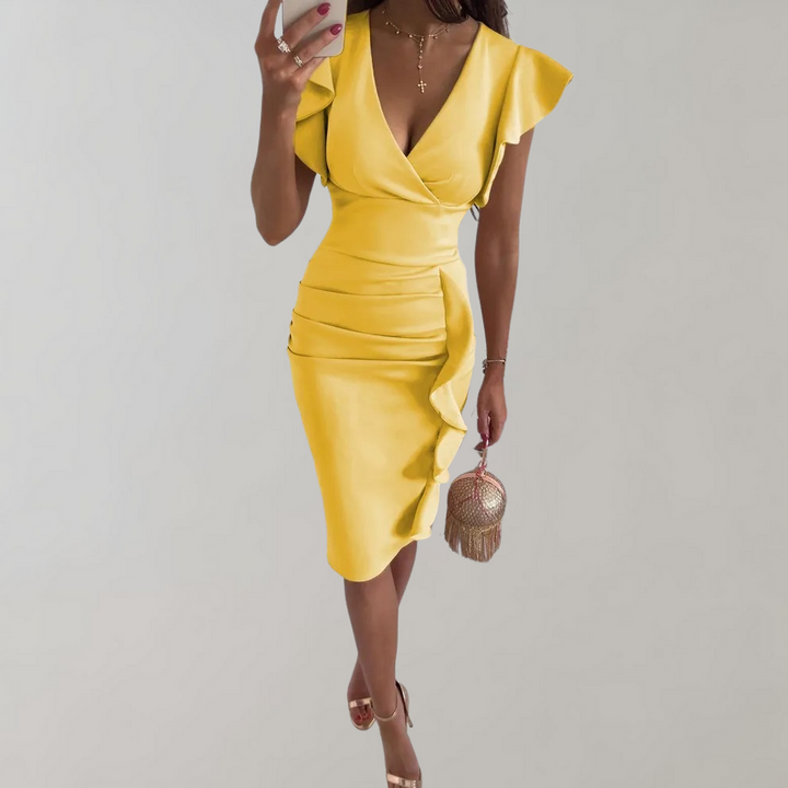Vrouw in gele jurk met ruches en V-hals, houdt een kleine tas vast. Perfect voor zomermode, elegante avondkleding, trendy dameskleding.