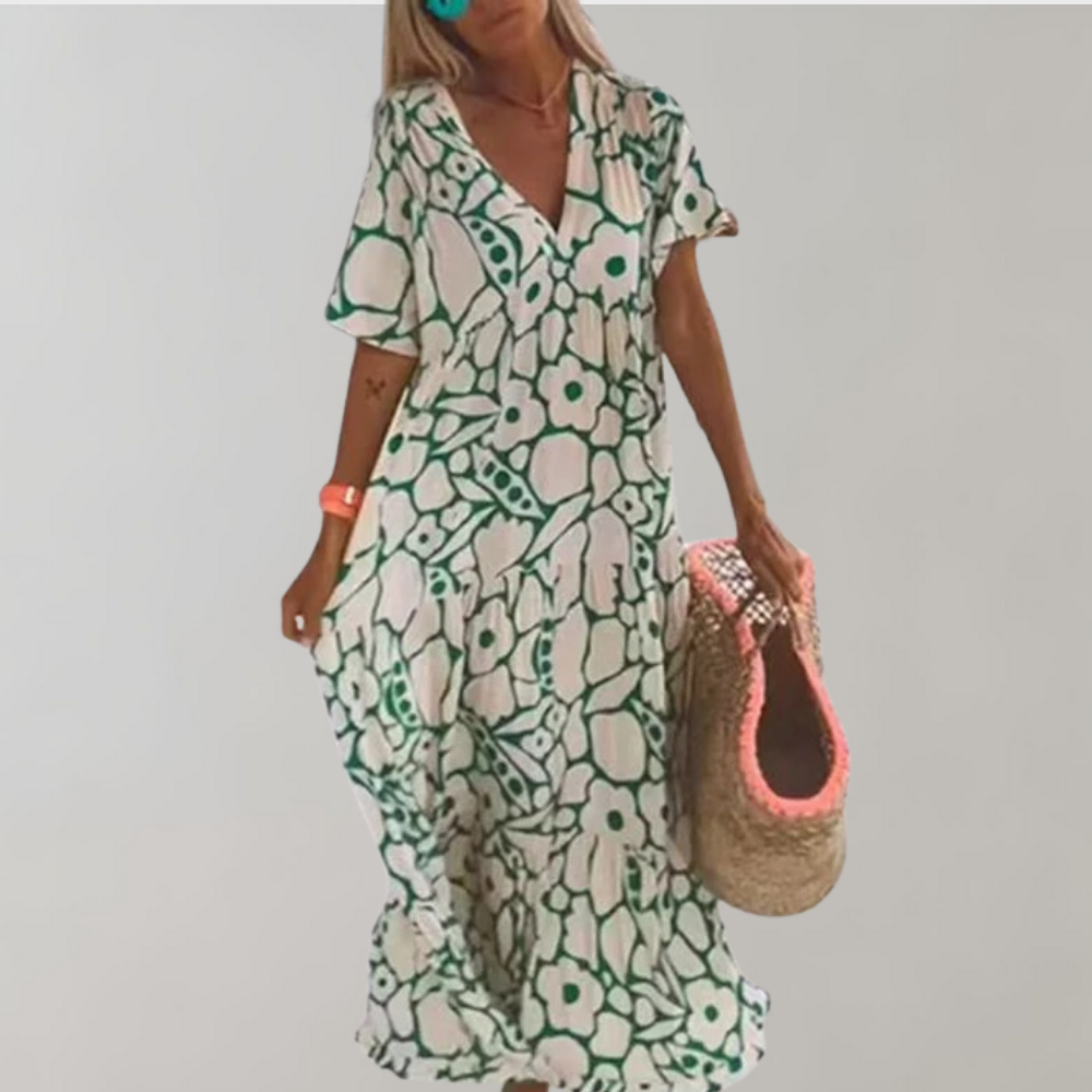 Vrouw in lange groene bloemenjurk met korte mouwen, draagt een rieten tas. Zomerse boho-stijl, casual mode, strandoutfit.