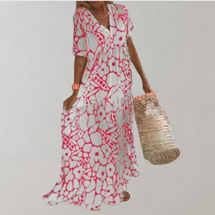Rode en witte bloemenjurk met korte mouwen, gedragen door een vrouw met een rieten tas. Zomerse boho-stijl, perfect voor stranduitjes.