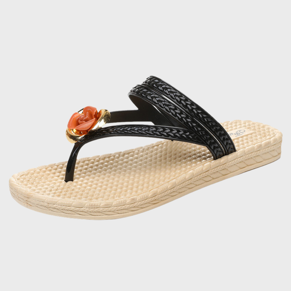 Zwarte teenslipper met gevlochten bandjes en oranje bloemdetail, comfortabele beige zool. Perfect voor zomerse dagen en stranduitjes.