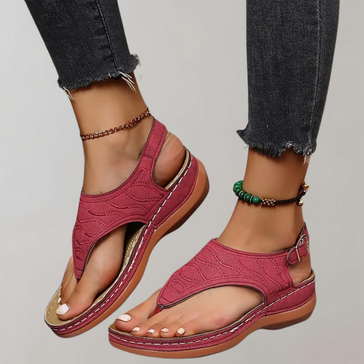 Rode sandalen met open teen en verstelbare band, gedragen met zwarte jeans en enkelarmbanden. Comfortabele zomerschoenen voor dames.