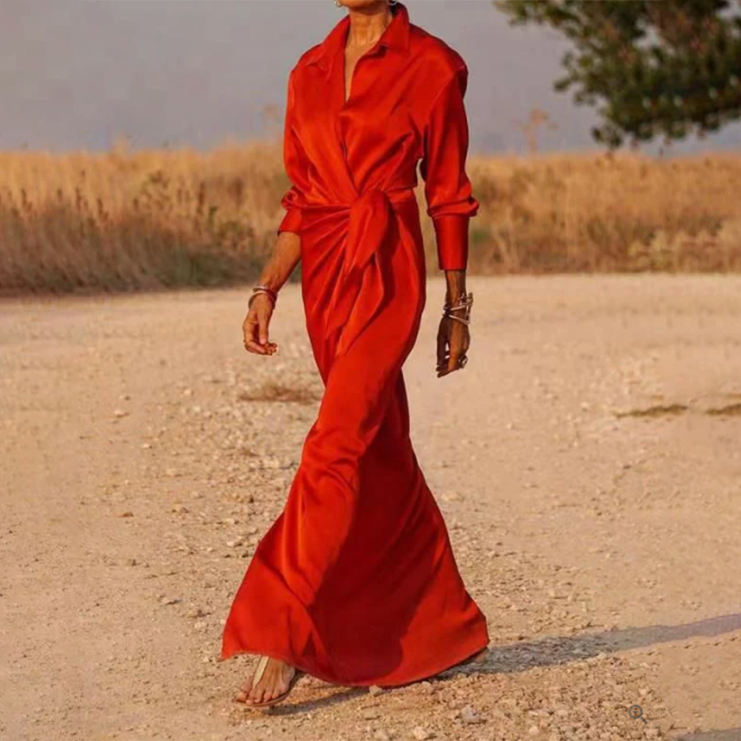 Rode lange lentejurk met lange mouwen, gedragen door een model op een landweg. Elegante damesmode, perfect voor warme seizoenen.