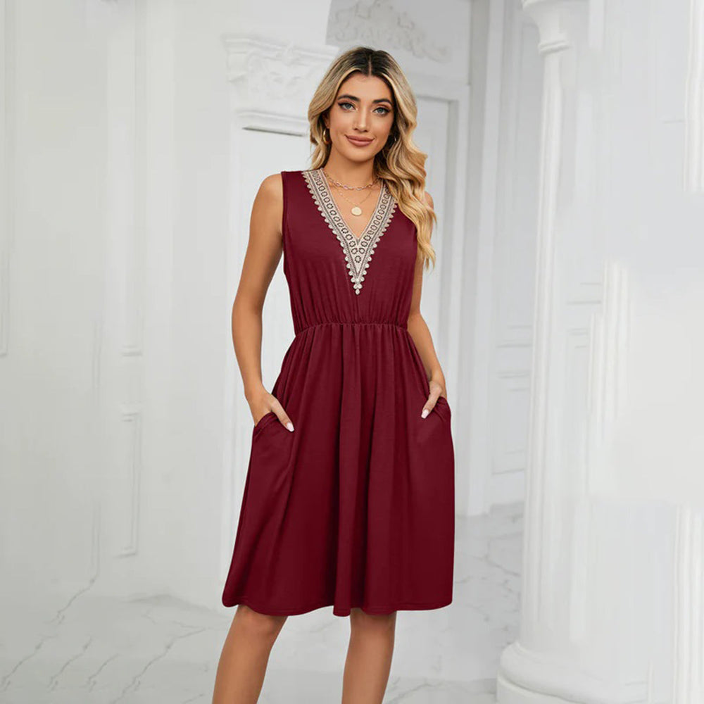 Vrouw in elegante bordeauxrode jurk met V-hals en kanten details, staand in lichte kamer. Mode, dameskleding, stijlvolle jurk, casual chic.