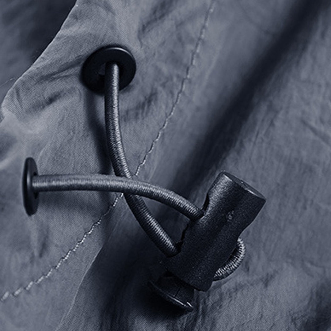 Grijze waterdichte jas met trekkoordsluiting en zwarte stopper, close-up. Outdoor kleding, regenjas, duurzame stof.