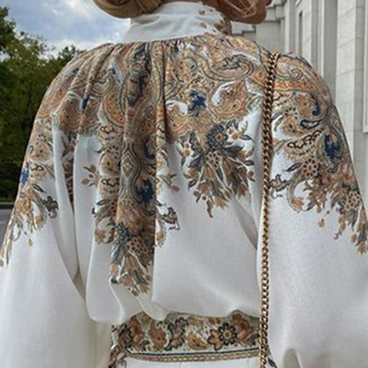Witte blouse met kleurrijk paisley-patroon en gouden kettingdetail, elegante damesmode, bohemian stijl, buiten gefotografeerd.