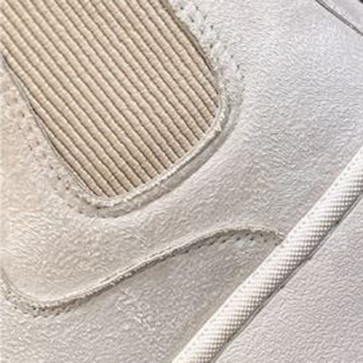 Close-up van een beige leren sneaker met geribbelde textuur en witte zool. Moderne herenschoen, casual stijl, hoogwaardige materialen.