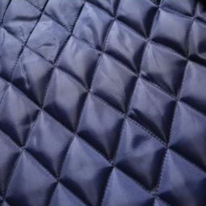 Donkerblauwe gewatteerde stof met diamantpatroon, close-up. Ideaal voor jassen, dekens en interieurdecoratie. Hoogwaardige textielmaterialen.