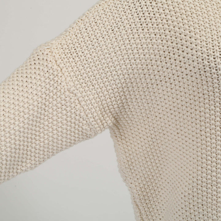 Beige gebreide trui detail, close-up textuur. Modieuze dameskleding, herfst-winter collectie, comfortabele en stijlvolle gebreide stof.