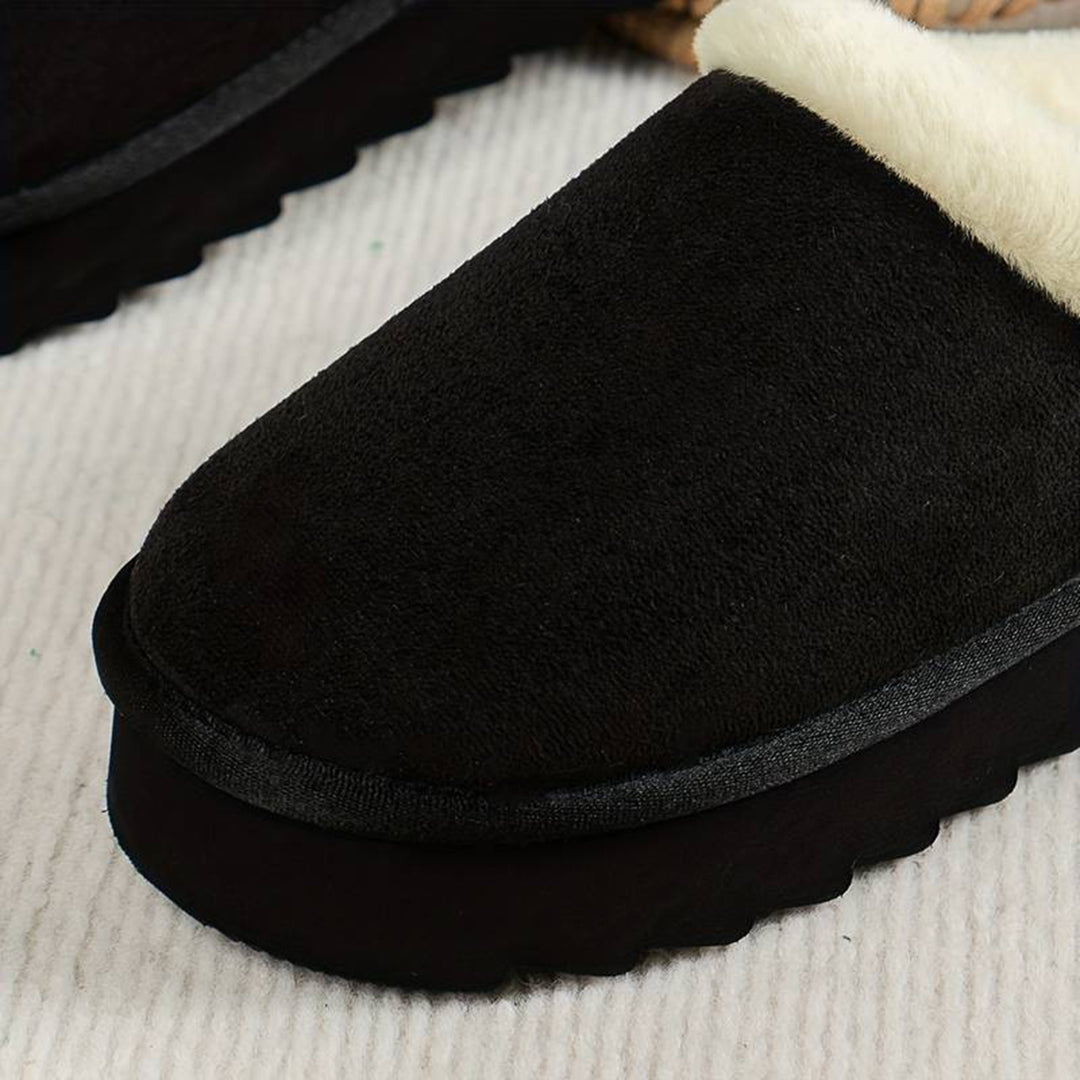 Zwarte suède pantoffel met witte voering, comfortabele winterse huisschoen, warme binnenzool, antislip zool, ideaal voor koude dagen.
