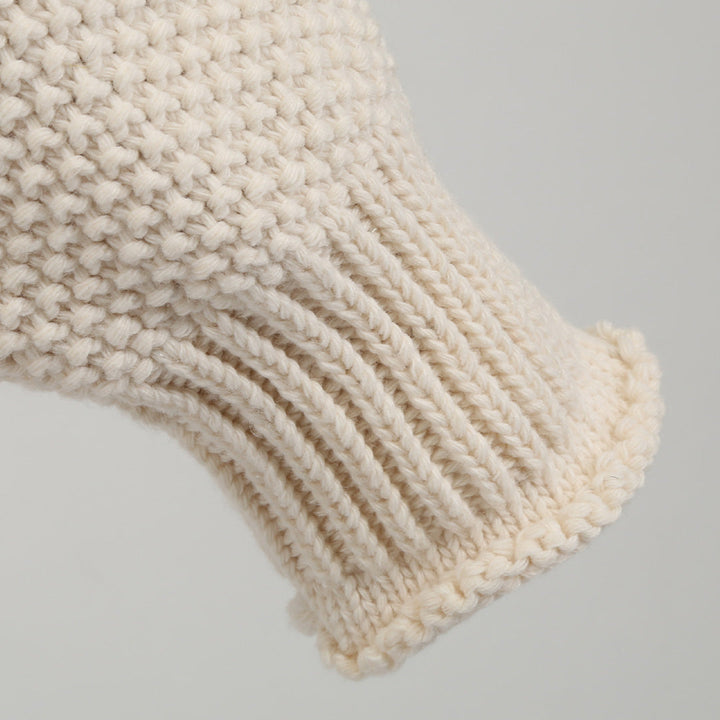 Beige gebreide mouw van wollen trui, close-up. Textuur en patroon van de stof, ideaal voor wintermode en warme kleding.