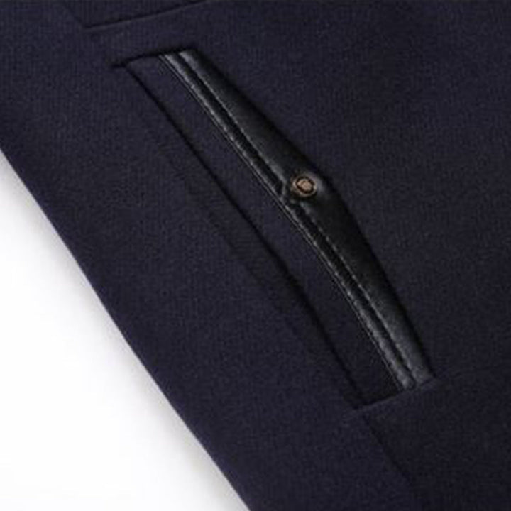 Donkerblauwe broek met zwarte leren zakdetail, stijlvolle herenmode, hoogwaardige stoffen, moderne kledingstijl, close-up afbeelding.