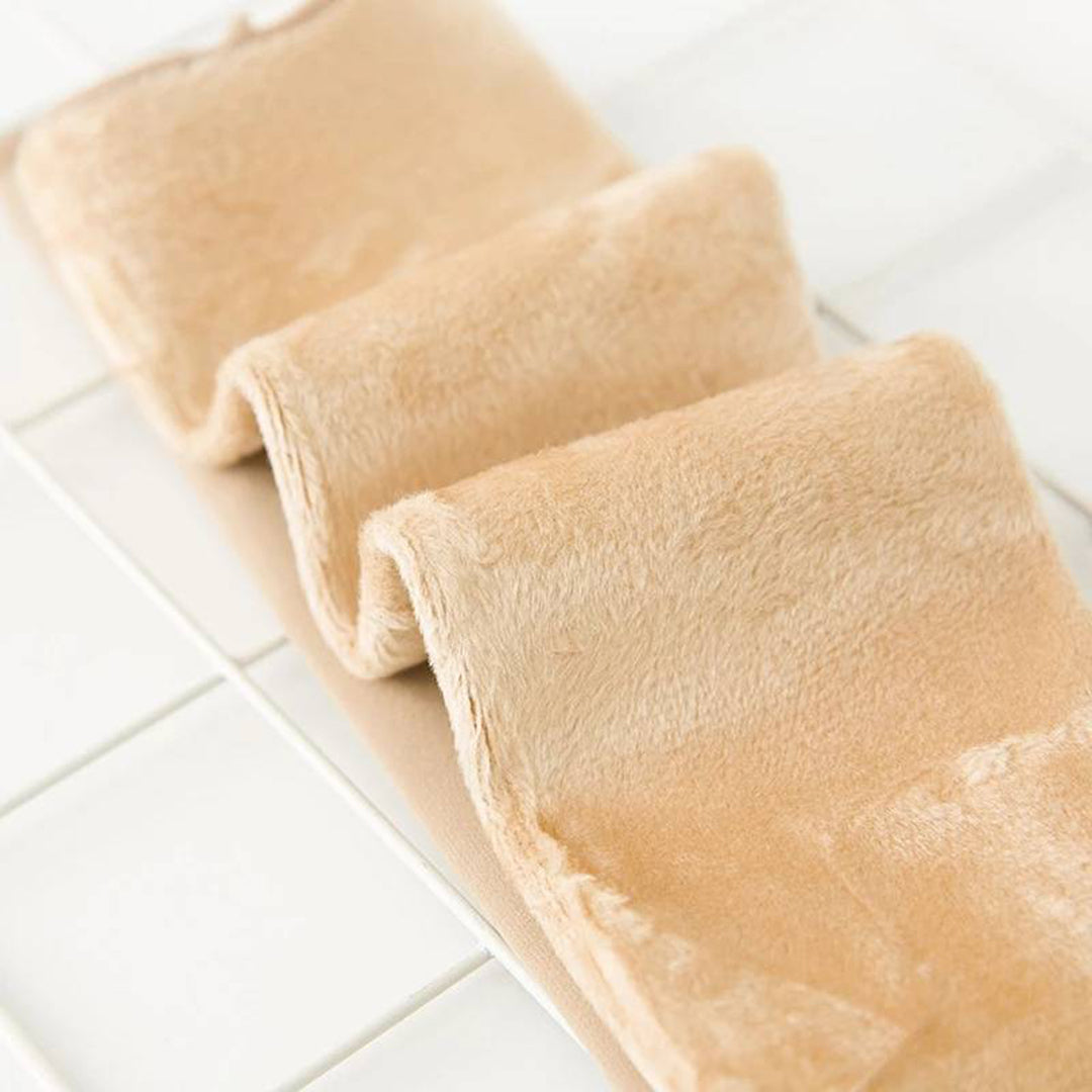 Zachte beige fleece deken op witte tegelvloer, close-up. Perfect voor winter, huisdecoratie, comfort en warmte. Luxe en knusse textuur.