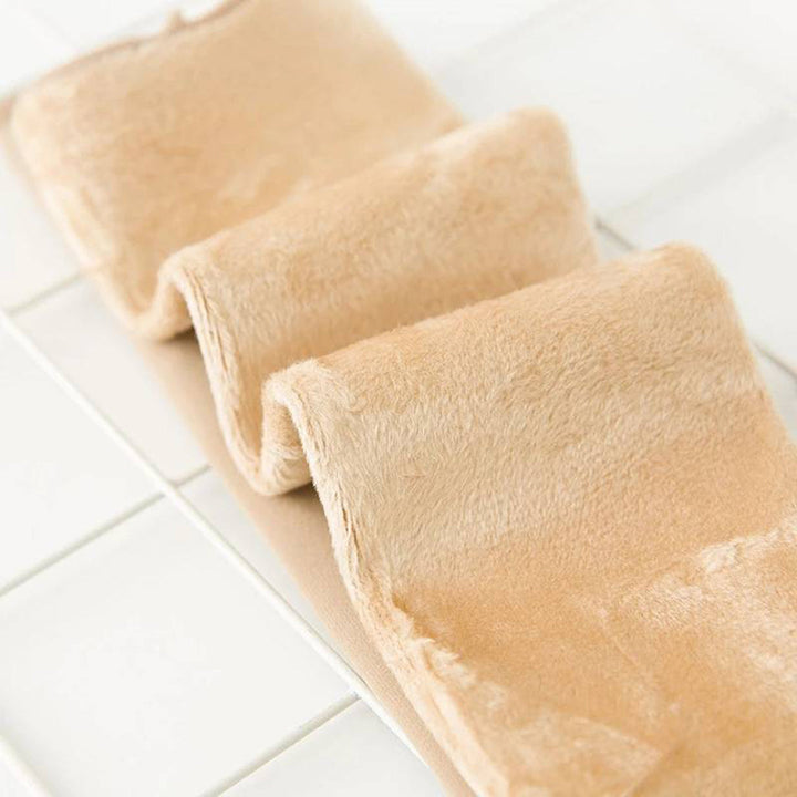 Zachte beige fleece deken op witte tegelvloer, close-up. Perfect voor winter, huisdecoratie, comfort en warmte. Luxe en knusse textuur.