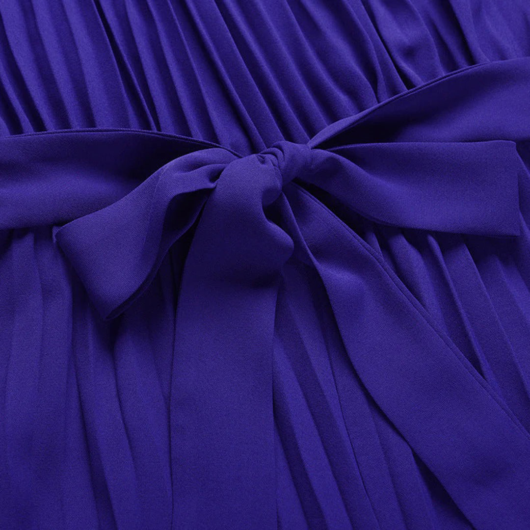 Paarse geplooide jurk met strikdetail, elegante damesmode, stijlvolle avondkleding, hoogwaardige stof, trendy design, perfect voor speciale gelegenheden.