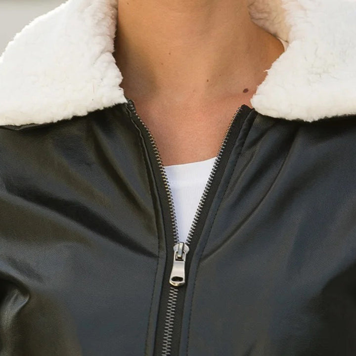 Zwarte leren jas met witte schapenvacht kraag, ritssluiting en witte top. Stijlvolle wintermode, warme damesjas, trendy kleding.
