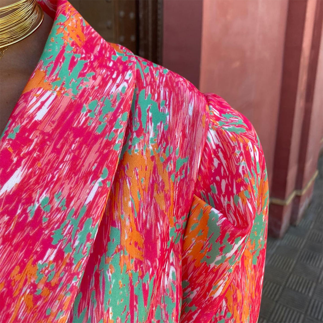 Felroze en oranje abstracte print op kleurrijke blouse, close-up. Modieuze dameskleding, levendige patronen, trendy design.