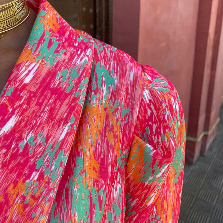 Felroze en oranje abstracte print op kleurrijke blouse, close-up. Modieuze dameskleding, levendige patronen, trendy design.