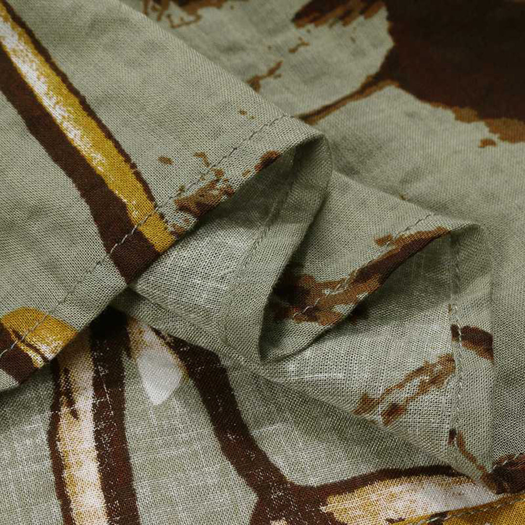 Groene linnen stof met abstract bruin en geel patroon, close-up. Hoogwaardige textieltextuur, geschikt voor mode en interieurontwerp.