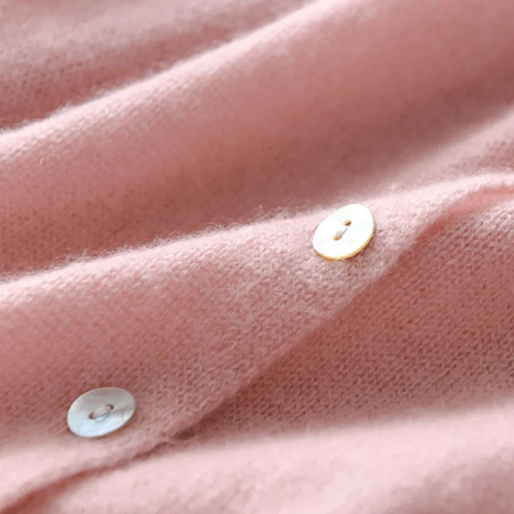 Roze kasjmier trui close-up met parelmoer knopen, zachte textuur. Luxe damesmode, warme winterkleding, premium kwaliteit.