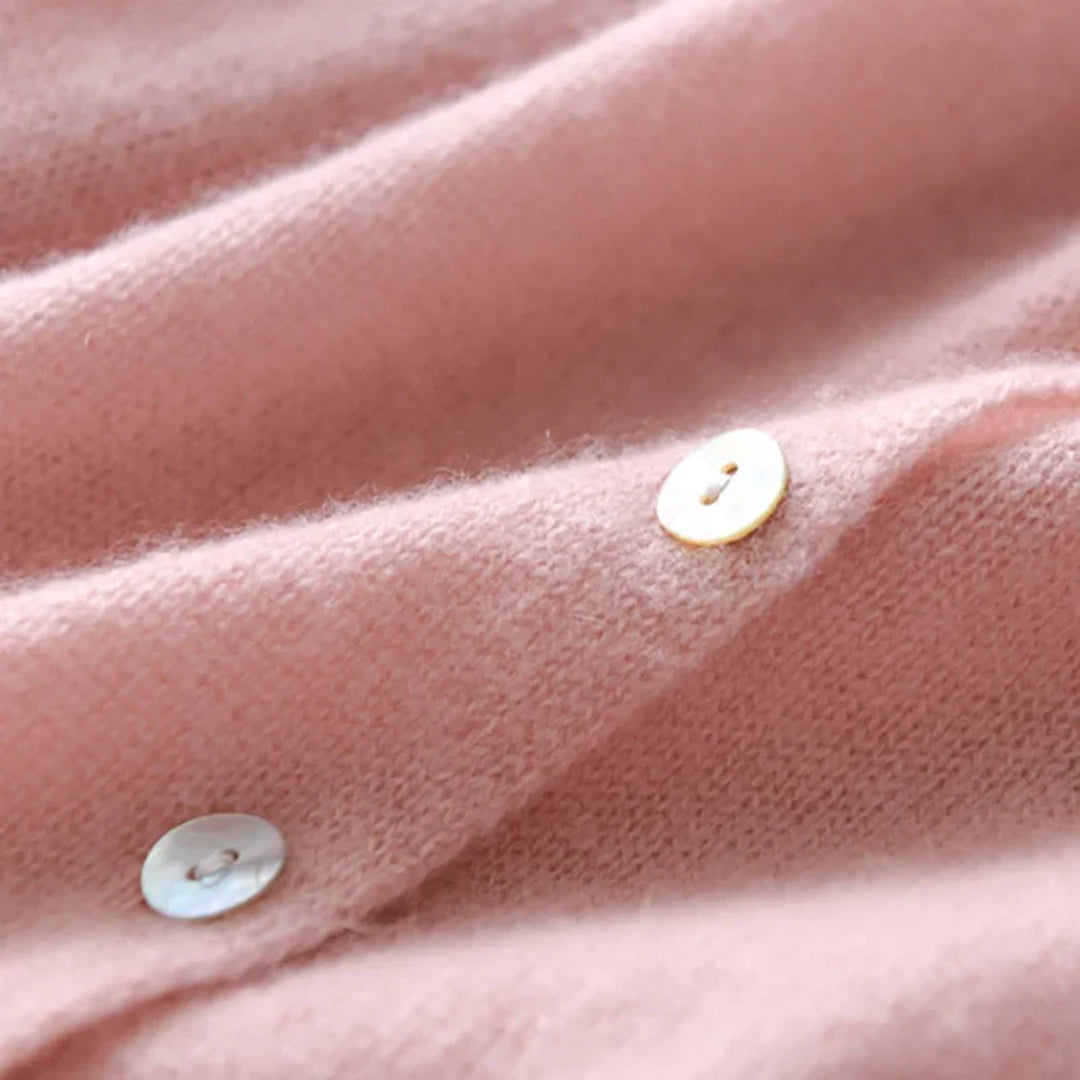 Roze kasjmier trui close-up met parelmoer knopen, zachte textuur. Luxe damesmode, warme winterkleding, premium kwaliteit.