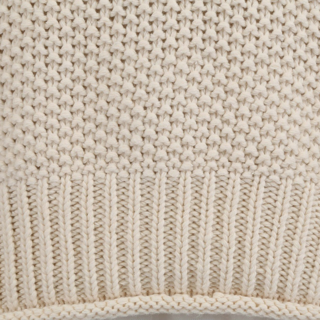 Beige gebreide trui textuur, close-up van katoenen breisel met ribbelpatroon. Perfect voor herfstmode en warme winterkleding.