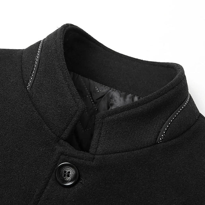 Zwarte wollen jas met opstaande kraag en knoopsluiting, detail van stiksels zichtbaar. Stijlvolle herenkleding, wintermode, warme jas.