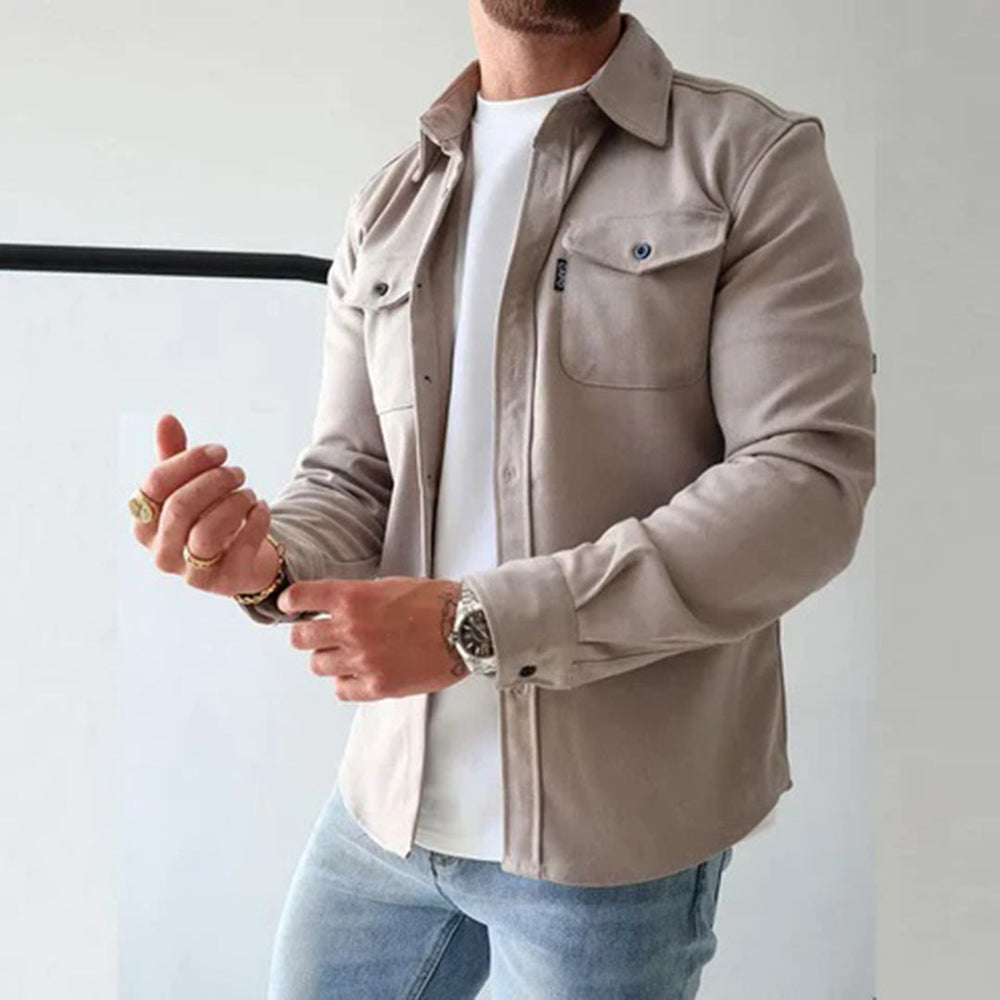 Man in beige overhemdjack, witte T-shirt en blauwe jeans. Modieuze herenkleding, casual stijl, lange mouwen, knoopsluiting, borstzakken.