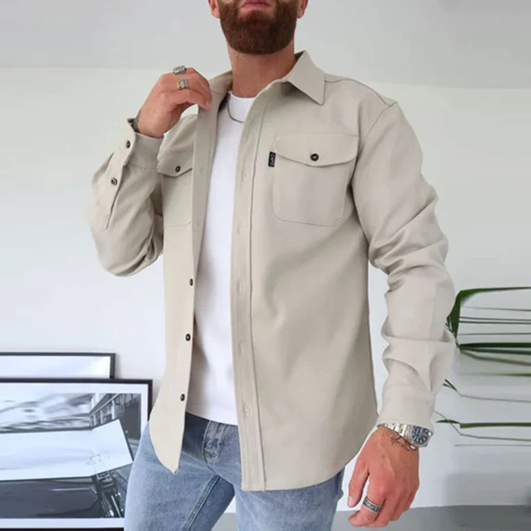 Man in beige overhemd met lange mouwen, gedragen over een wit T-shirt en blauwe jeans. Stijlvolle casual herenkleding, moderne mode.