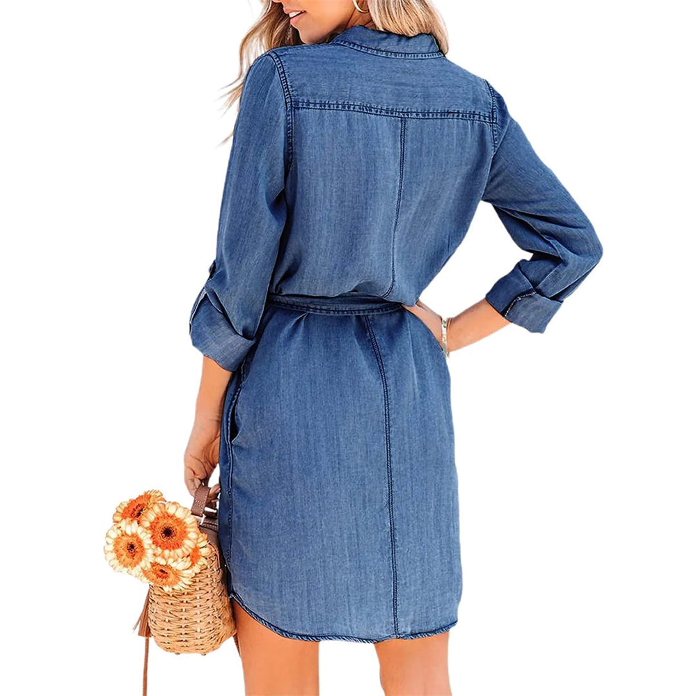 Vrouw in denim overhemdjurk met lange mouwen, draagt een rieten tas met oranje bloemen. Casual damesmode, blauwe spijkerjurk, trendy outfit.